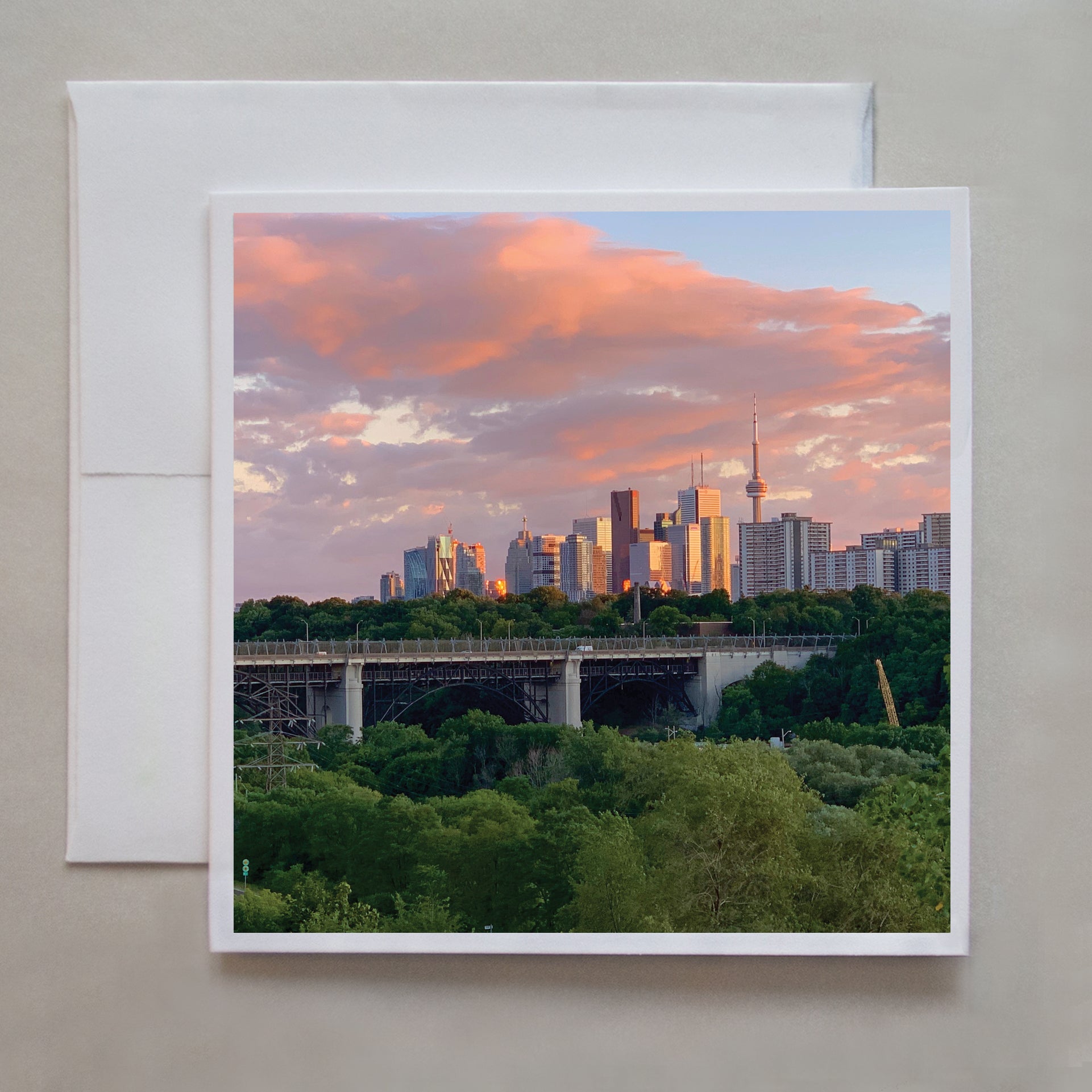 This photo card shows a gorgeous sunset with the Danforth bridge & CN Tower in the background and was photographed at the Chester Hill lookout by Toronto photographer, Caley Taylor.