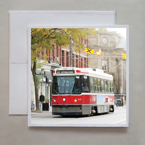 This is a greeting card of an old TTC streetcar running along Queen Street East with the Queen & Saulter library in behind by photographer Caley Taylor.