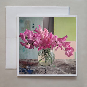 Spring sweet pea blossoms are sitting in a mason jar with a colourful artist's studio background by photographer Jennifer Echols. 