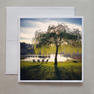 This greeting card of 4 muskoka chairs set under a a luscious weeping willow overlooking a pond gives a calming feeling on a early summer evening.  Photographer Jennifer Echols.