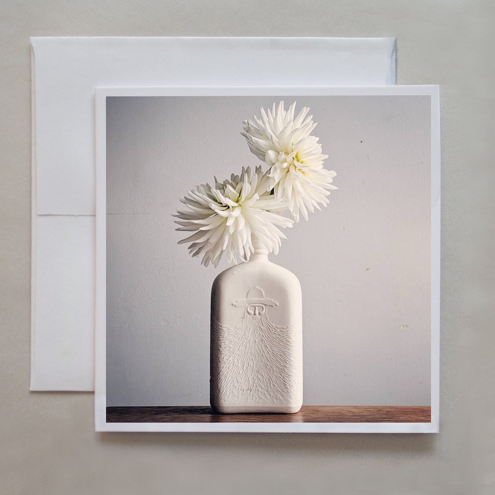 White dahlias stand in a white painted bottle with soft side lighting by photographer Jennifer Echols. 